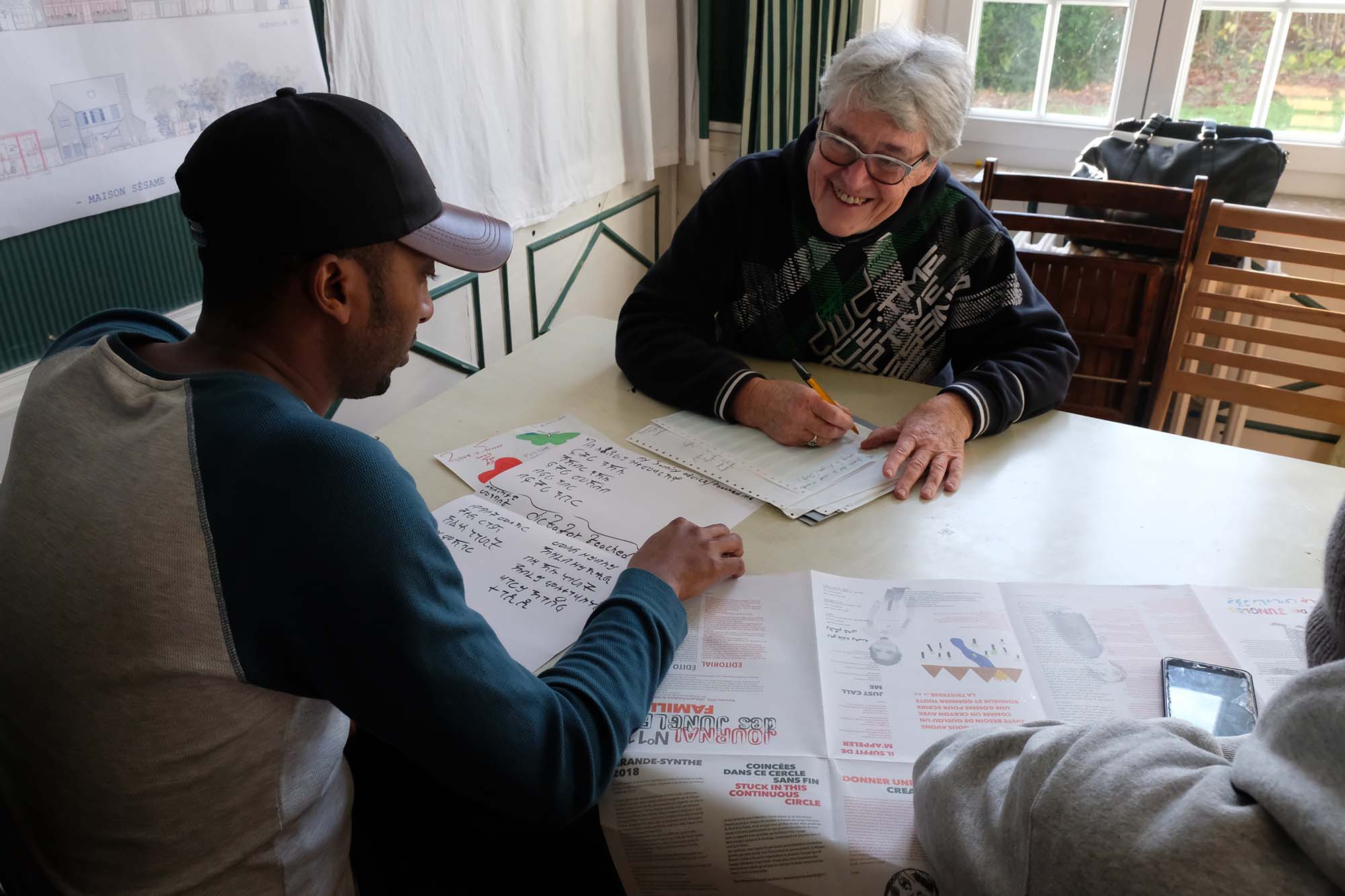 Eve-Marie, bénévole de longue date à Calais, aide Robel à écrire son texte